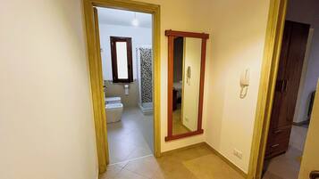 Un pasillo con un baño visible a través de una puerta abierta.