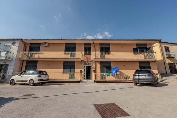 A two-story building with a central entrance, balconies, and parked cars. - B&B Margherita (Sant'Angelo dei Lombardi)