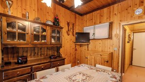 Ein Zimmer mit Holzwänden, einem Bett, einem Fernseher, einem Schrank und einer Uhr.