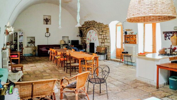 Un vaste espace dédié à la salle à manger, avec une grande table et des chaises en bois, une cheminée en pierre et un luminaire suspendu en osier.