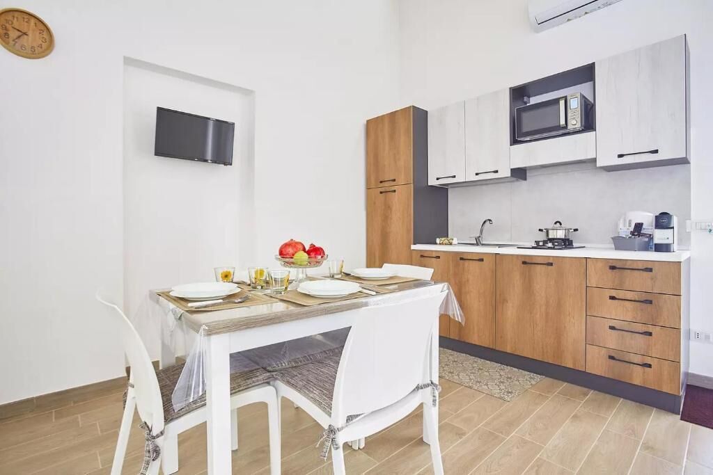 Cuina moderna amb armaris blancs, un microones i zona de menjador amb taula preparada per a dues persones.