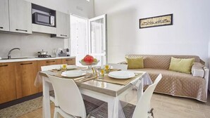 A compact living space with a dining area, kitchenette, and a sofa. - Casale Sammartano By L.A.Apartments (Ummari)