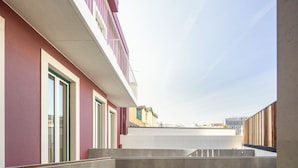 A modern building with a flat roof terrace, large windows, and a view of the cityscape. - LSA Avenida by Numa (Lisbon)