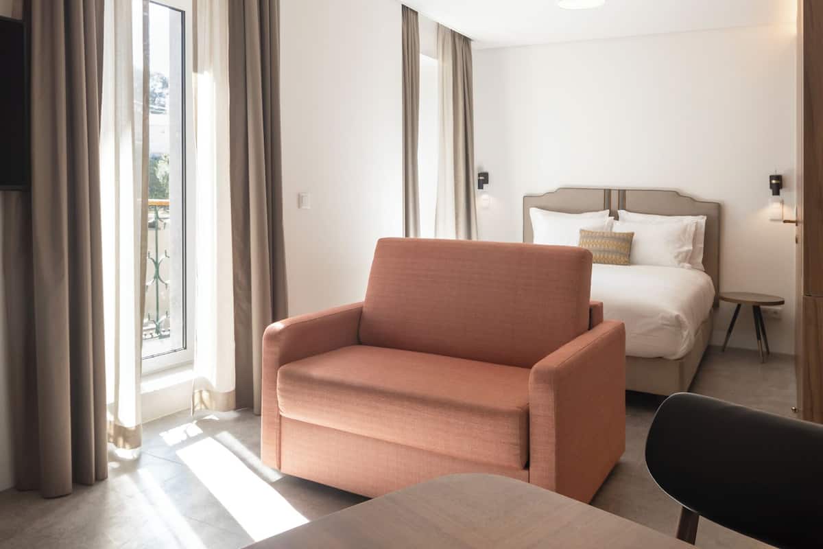 Een moderne hotelkamer met een bank, een bed, een klein tafeltje en een televisie.