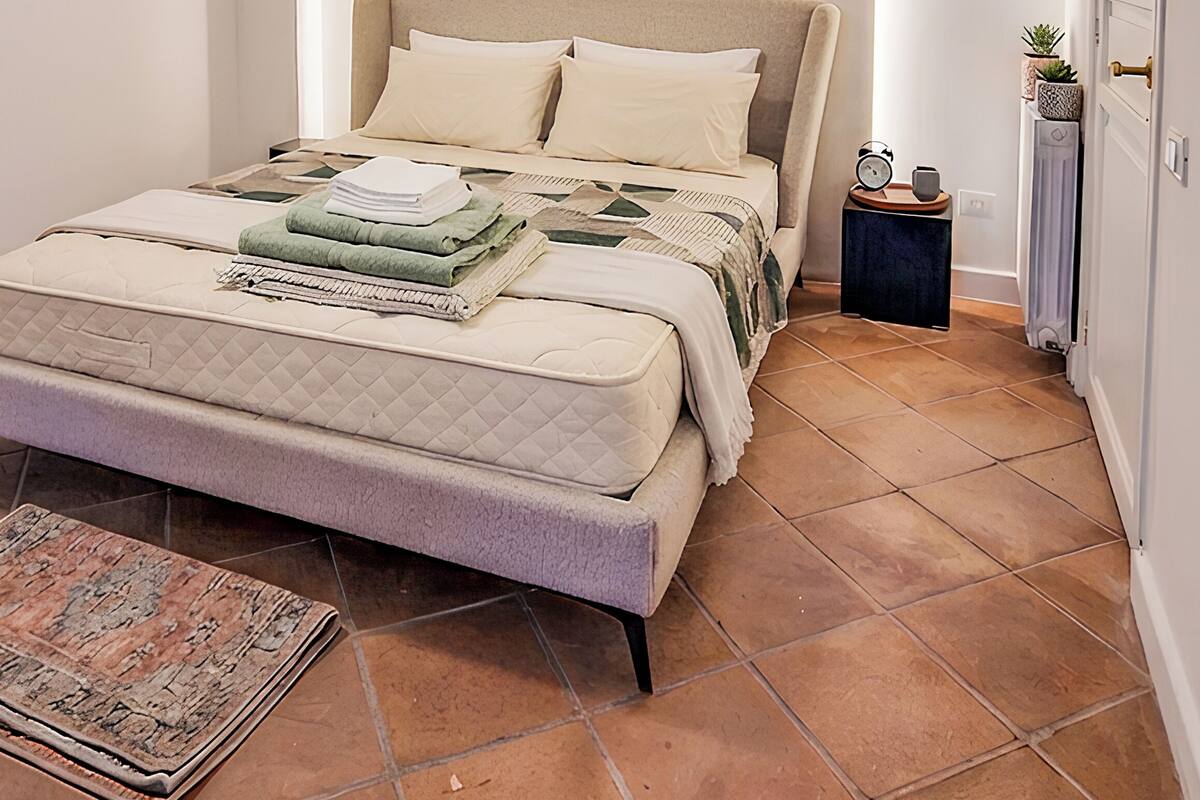 Un dormitorio con cama, mesita de noche y velador.
