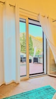 Quarto com porta de vidro deslizante que dá para um alpendre ao ar livre com vista para uma paisagem montanhosa.