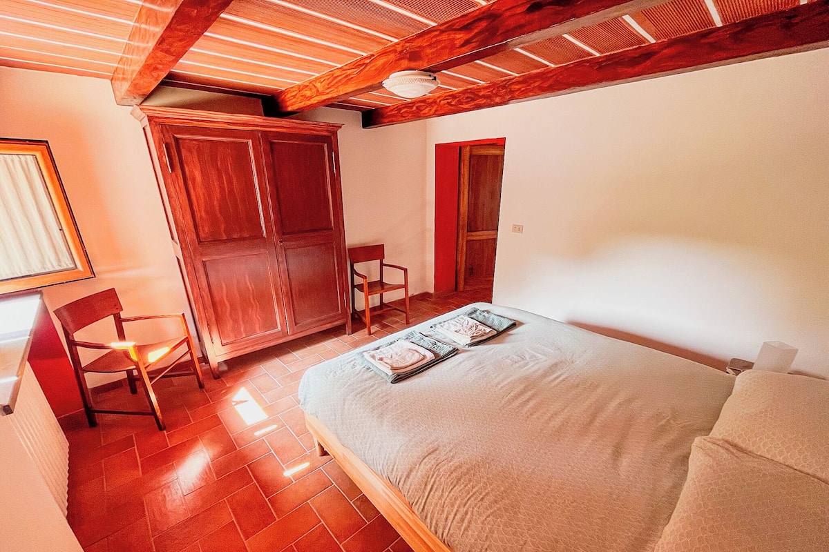 A bedroom with a bed, wooden wardrobe, and a chair.