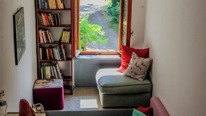 A cozy room with a window, a bookshelf, a sofa, and a small table. - Podere tra gli Ulivi (Parrano)