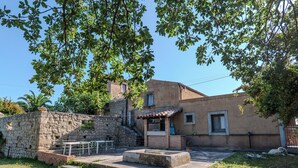 A stone wall, a small outdoor seating area, and a building with a tiled roof. - Agriturismo Baglio San Pietro (Nicosia)
