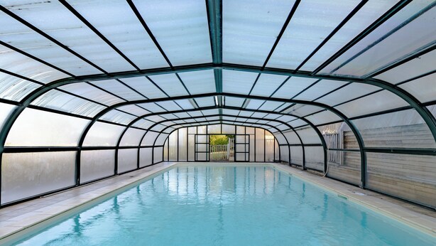 A large indoor swimming pool with a curved roof structure.