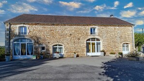 A stone building with a symmetrical facade, large arched windows, and a central entrance.