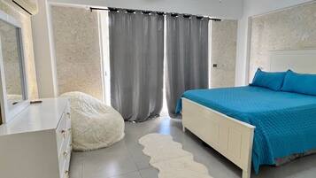 A bedroom with a bed, a dresser, a ceiling fan, and a window with curtains.