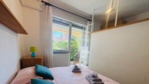 A bedroom with a bed, pillows, a bedside table with a lamp, and a view of the outside. - GRAZIELLA - Fronte Mare in Centro con terrazza (Marina di Andora)