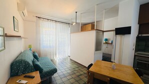 A compact living space with a sofa, a small table, a TV, and a kitchenette. - GRAZIELLA - Fronte Mare in Centro con terrazza (Marina di Andora)
