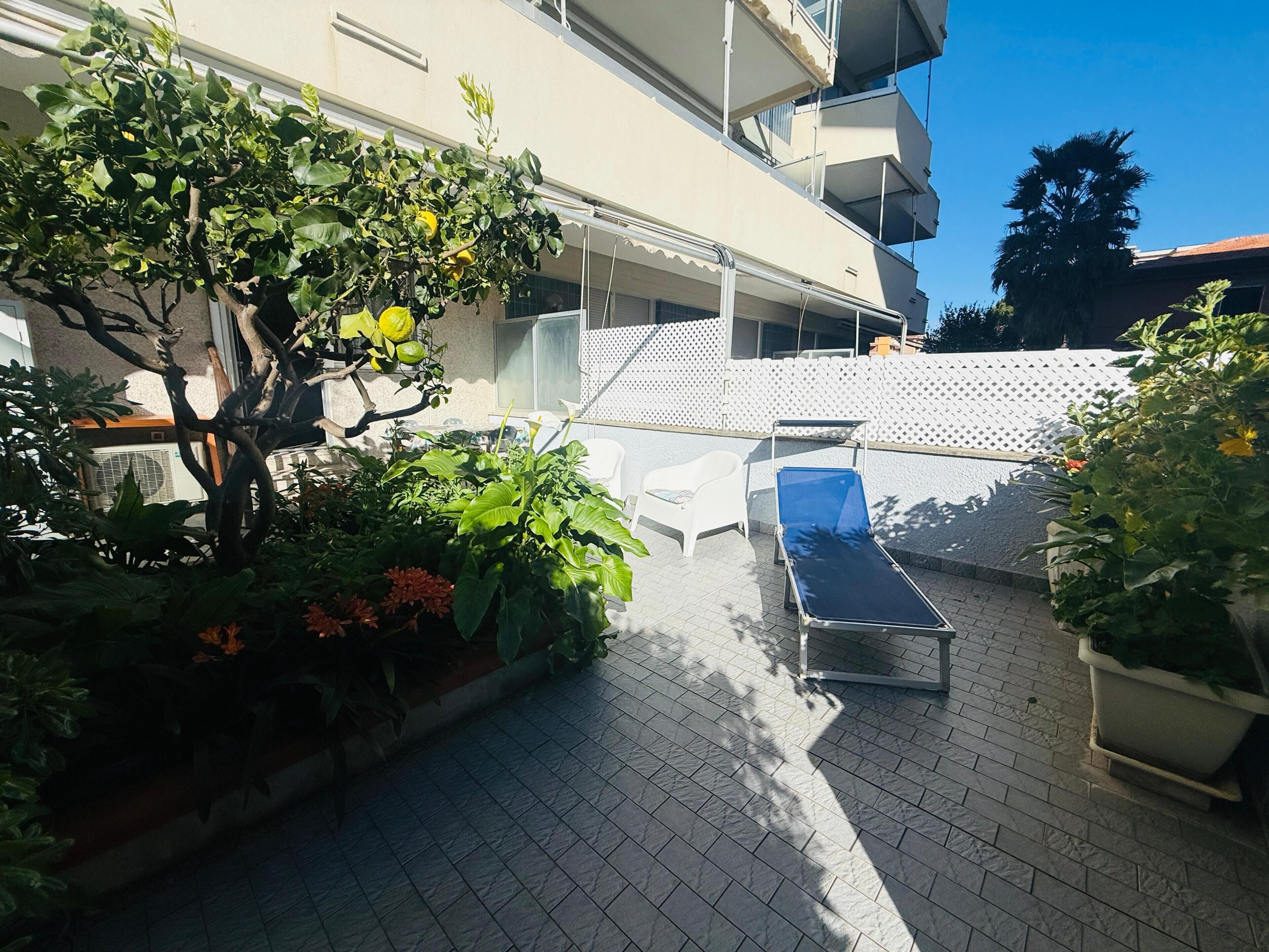 Une cour avec un transat, des plantes en pot et un bâtiment doté de balcons.