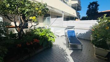 Une cour avec un transat, des plantes en pot et un bâtiment doté de balcons.