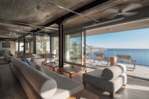 Ein modernes Interieur mit einer großen Couch, einem Couchtisch und einem Balkon mit Sitzgelegenheiten mit Blick auf das Meer.
