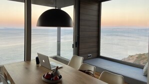 Ein modernes Interieur mit Esstisch, Stühlen, einem Laptop und einer Topfpflanze.