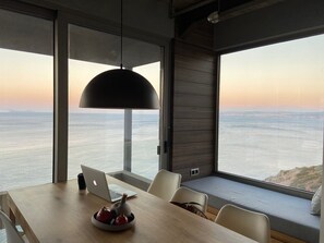 Ein modernes Interieur mit Esstisch, Stühlen, einem Laptop und einer Topfpflanze.
