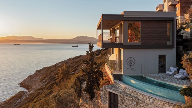 Ein modernes Gebäude mit einem Balkon mit Blick auf ein Gewässer, einen Pool und eine Berglandschaft.