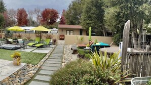 Un jardín trasero con zona de patio, mobiliario exterior y un gato.
