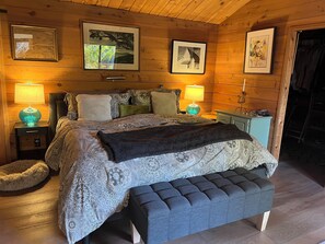 A cozy bedroom with a large bed, two bedside tables with lamps, a bench, and framed pictures on the walls. - Amazing 1-bedroom house in charming Carmel Valley perfect for relaxing (Carmel Valley)