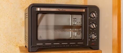 A black toaster oven with a control panel on a wooden shelf.