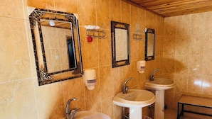Casa de banho com três lavatórios, duas espelhas e um banco.