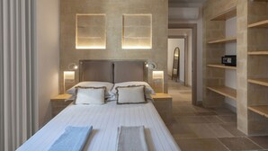 A modern hotel room with a large bed, two bedside tables with lamps, a headboard, and a built-in shelf unit. - Gattarella - Ville al mare (Vieste)