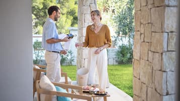A patio area with outdoor seating, a stone pillar, and a table with food and drinks.