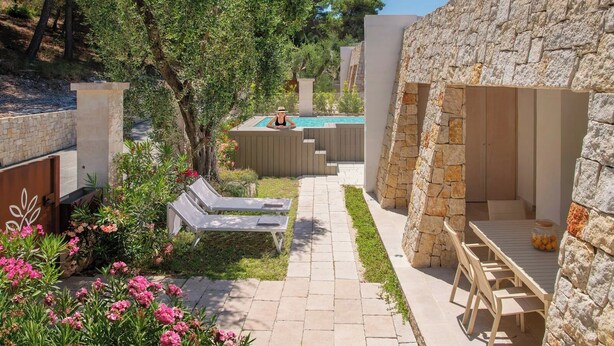 A pool area with lounge chairs, a stone wall, and a small garden with pink flowers. - Gattarella - Ville al mare (Vieste)