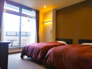 A hotel room with two beds, a table, and a chair near a window with a view. - PREMIUM TOJI (Kyoto)