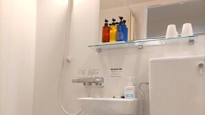 Kylpyhuone, jossa on kylpyamme, wc ja lasihylly, jossa on hygieniatuotteita.