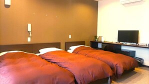 Hotellihuone, jossa on kaksi sänkyä, televisio, työpöytä ja ilmastointilaite.