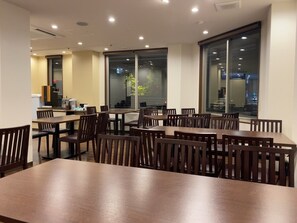 A dining area with multiple tables and chairs, large windows, and a kitchenette in the background. - PREMIUM TOJI (Kyoto)