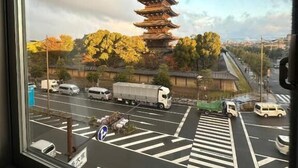 Perinteinen japanilainen pagodi näkyy ikkunan läpi, ja etualalla on parkkipaikka ja ajoneuvoja.