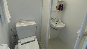 A compact bathroom with a toilet, sink, and shower area. - PREMIUM TOJI (Kyoto)