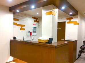 A reception desk with a digital display, a fire alarm, and a 'Fire Exit' sign. - PREMIUM TOJI (Kyoto)