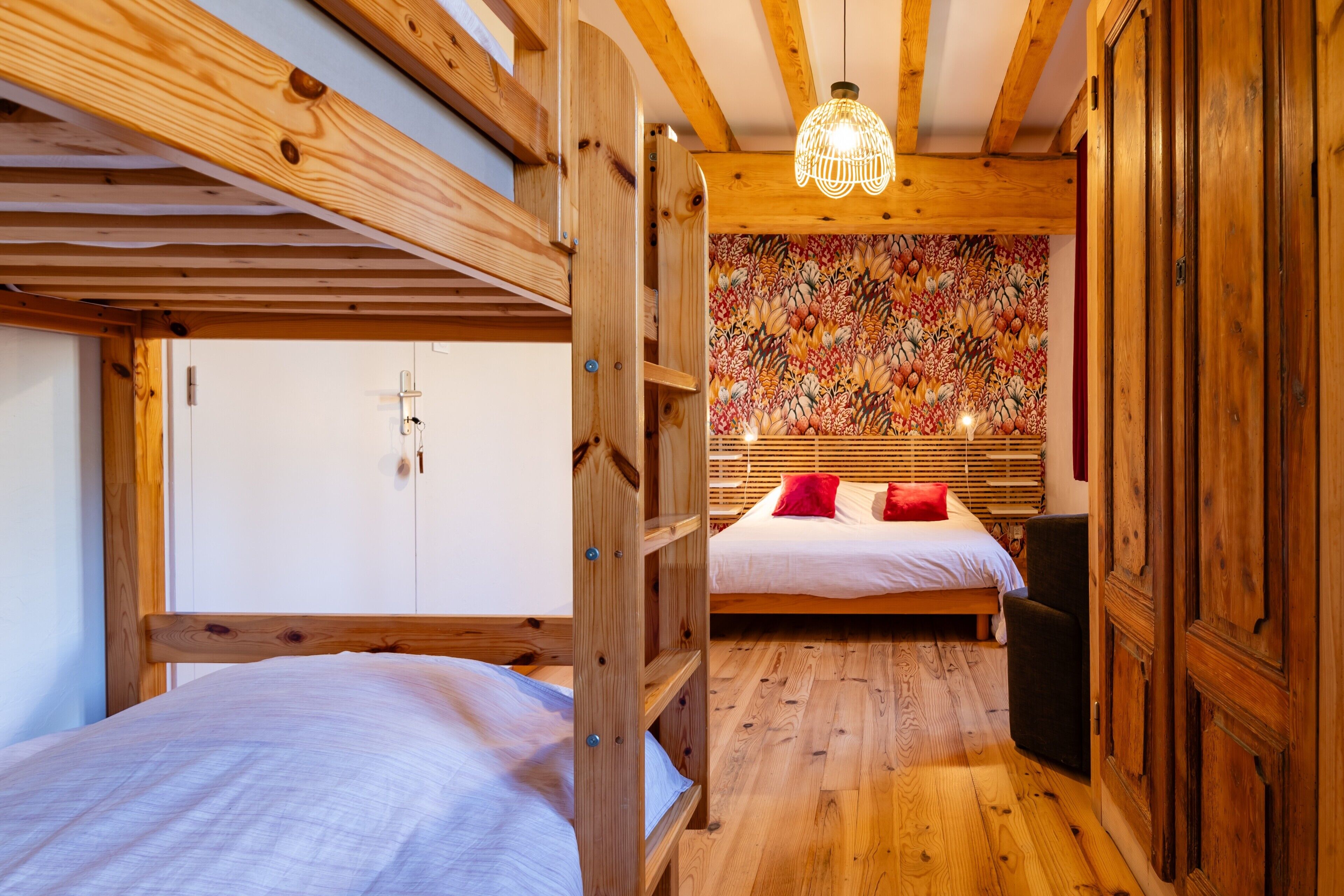 A wooden room with bunk beds, a wall with a floral pattern, and a hanging light fixture.