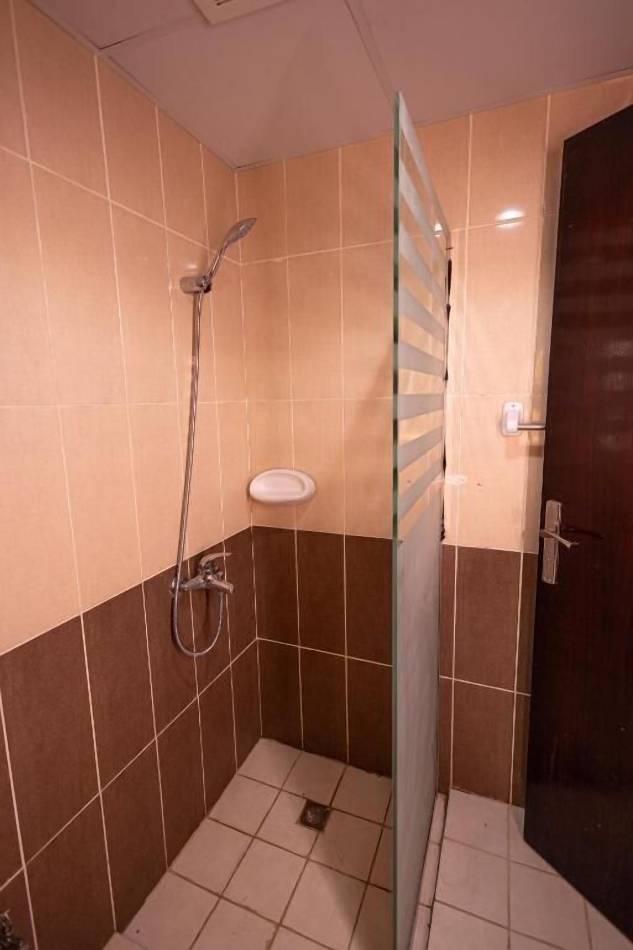 A small, tiled bathroom with a shower, a toilet, and a glass partition.