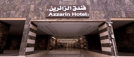 The entrance to the Azzarin Hotel with a marble facade and a sign in both Arabic and English.