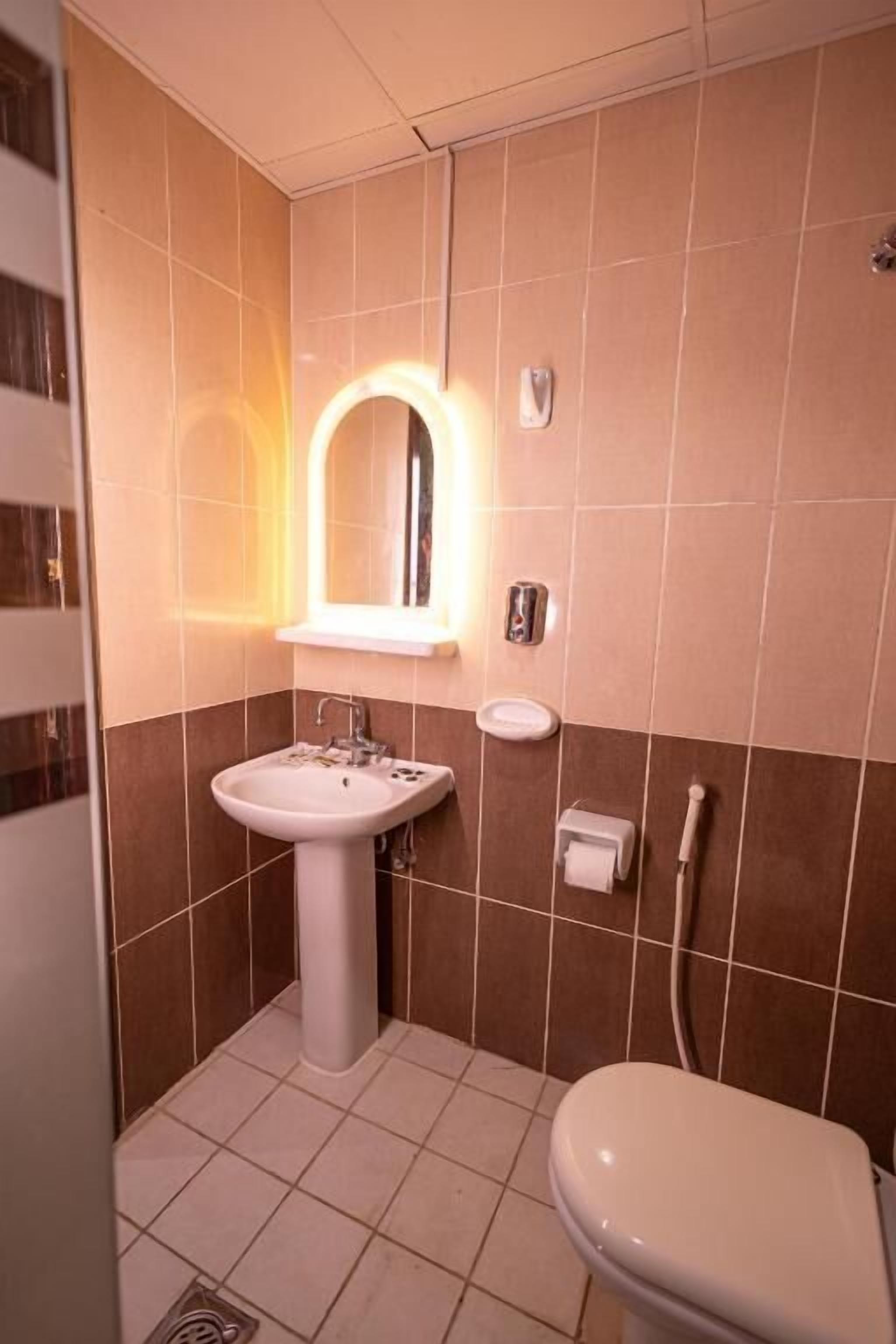 Un baño con lavamanos, espejo e inodoro.