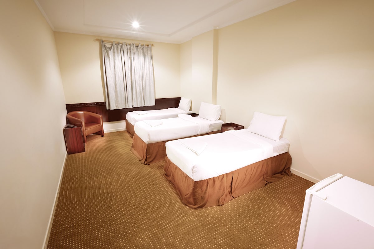 A hotel room with two beds, a desk, a chair, and a window with curtains.