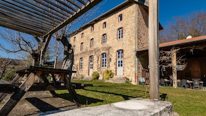 A stone building with multiple windows and a covered outdoor area with tables and chairs. - Guesthouse “La Chastanha - Room 2” with Mountain View (Saint-Symphorien de Mahun)