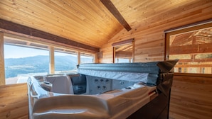 A wooden cabin interior with a hot tub, large windows, and a view of the mountains. - Guesthouse “La Chastanha - Room 2” with Mountain View (Saint-Symphorien de Mahun)