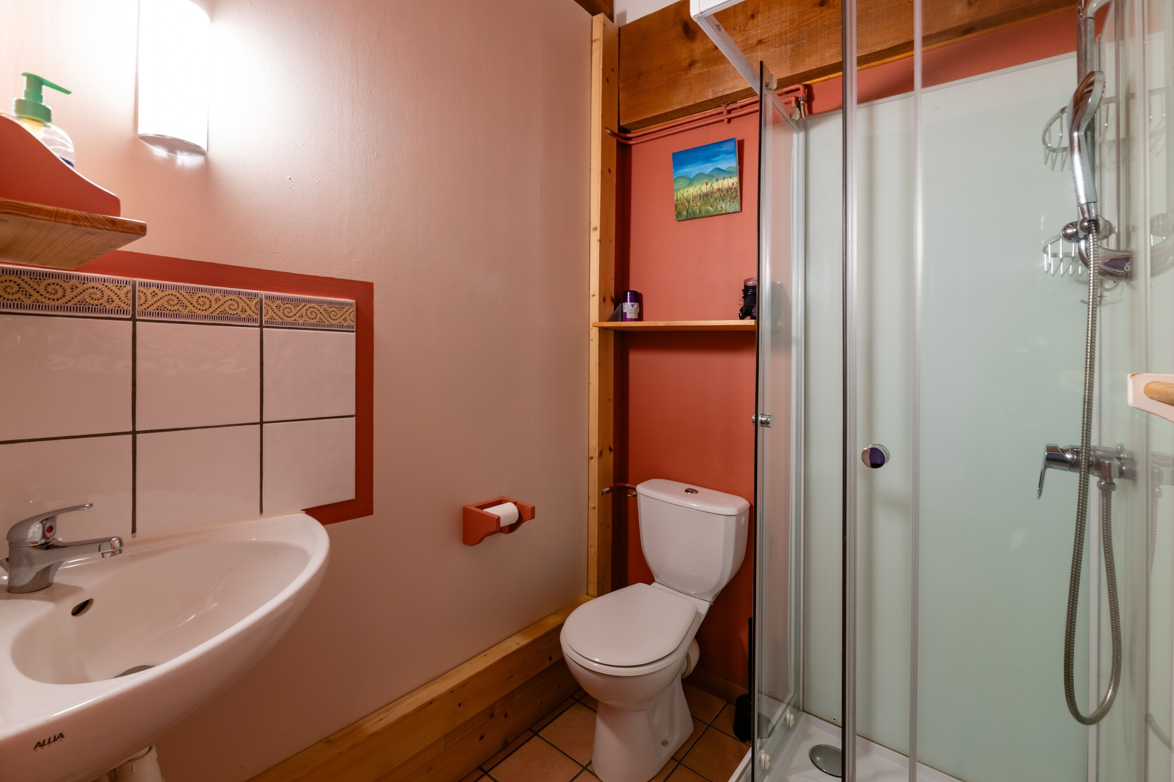 Une salle de bain avec un lavabo blanc, des toilettes et une douche à parois de verre.