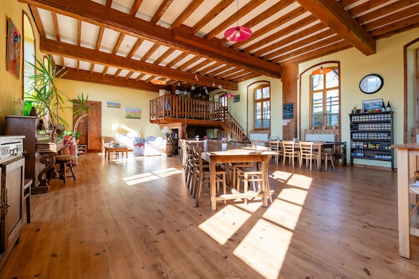 Une pièce spacieuse avec un plancher en bois, un balcon et un coin repas doté de meubles en bois.