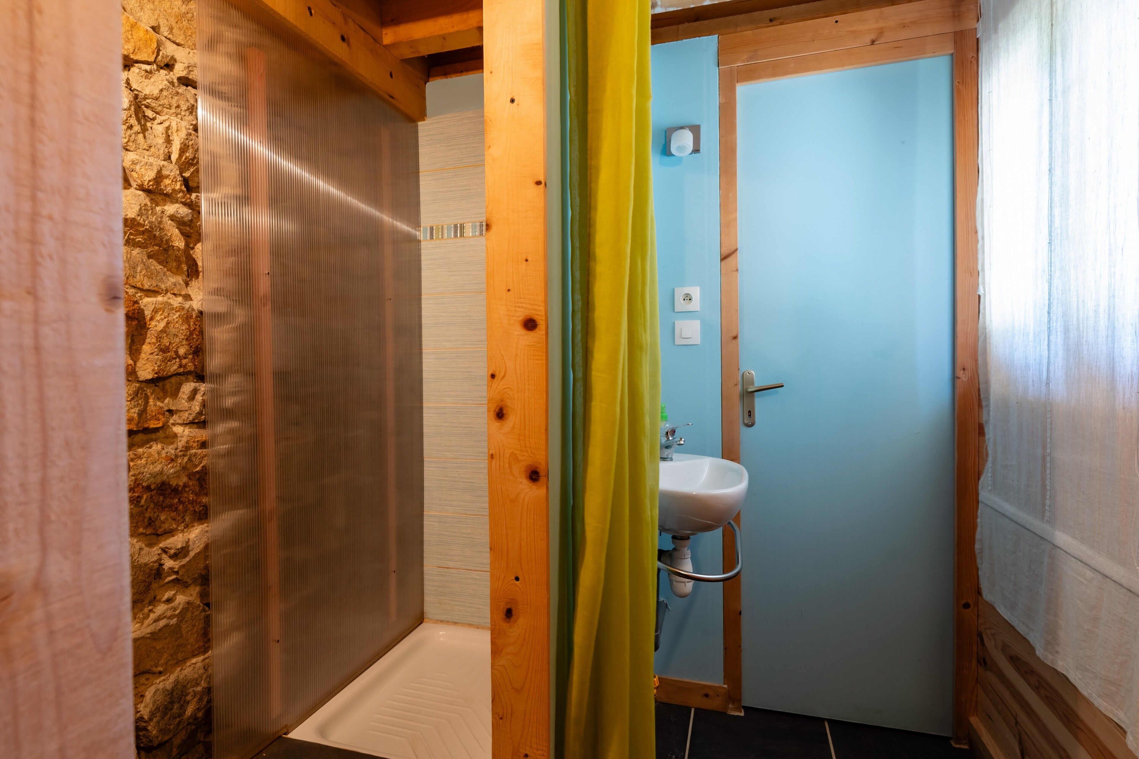 Ein Badezimmer mit Steinwand, Holztür und Waschbecken.