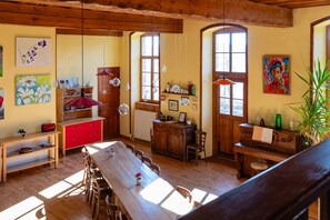 Un coin repas en bois avec une longue table et des chaises, un buffet rouge et une fenêtre donnant sur un beau paysage.