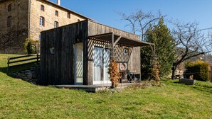 A rustic wooden building with a glass door, a small porch, and a stone wall. - Eco-Lodge Cabin in Ardèche Close to Nature (Saint-Symphorien de Mahun)